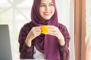 a lady enjoying coffee while doing her work with a laptop on the table