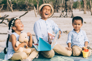 three siblings playing on the beachside laughing happily